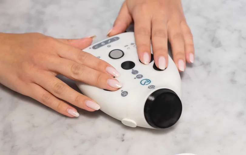 Hands holding the OmbuMed device against a wrist to record heart activity