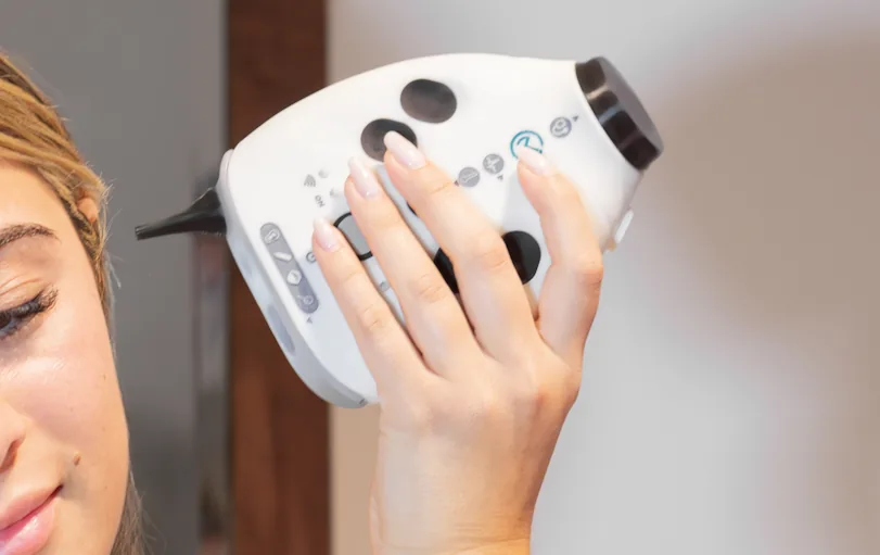 A person examining their ear with the OmbuMed otoscope attachment