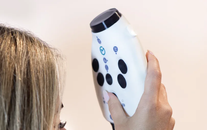 The OmbuMed device held near the forehead to take a contactless temperature reading