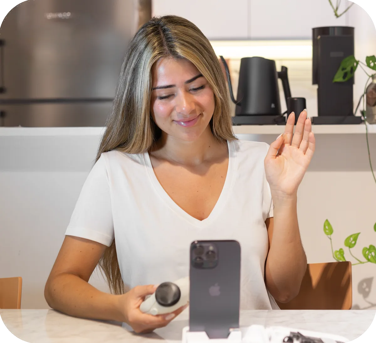 A patient waves to their doctor during a video consultation while holding the device