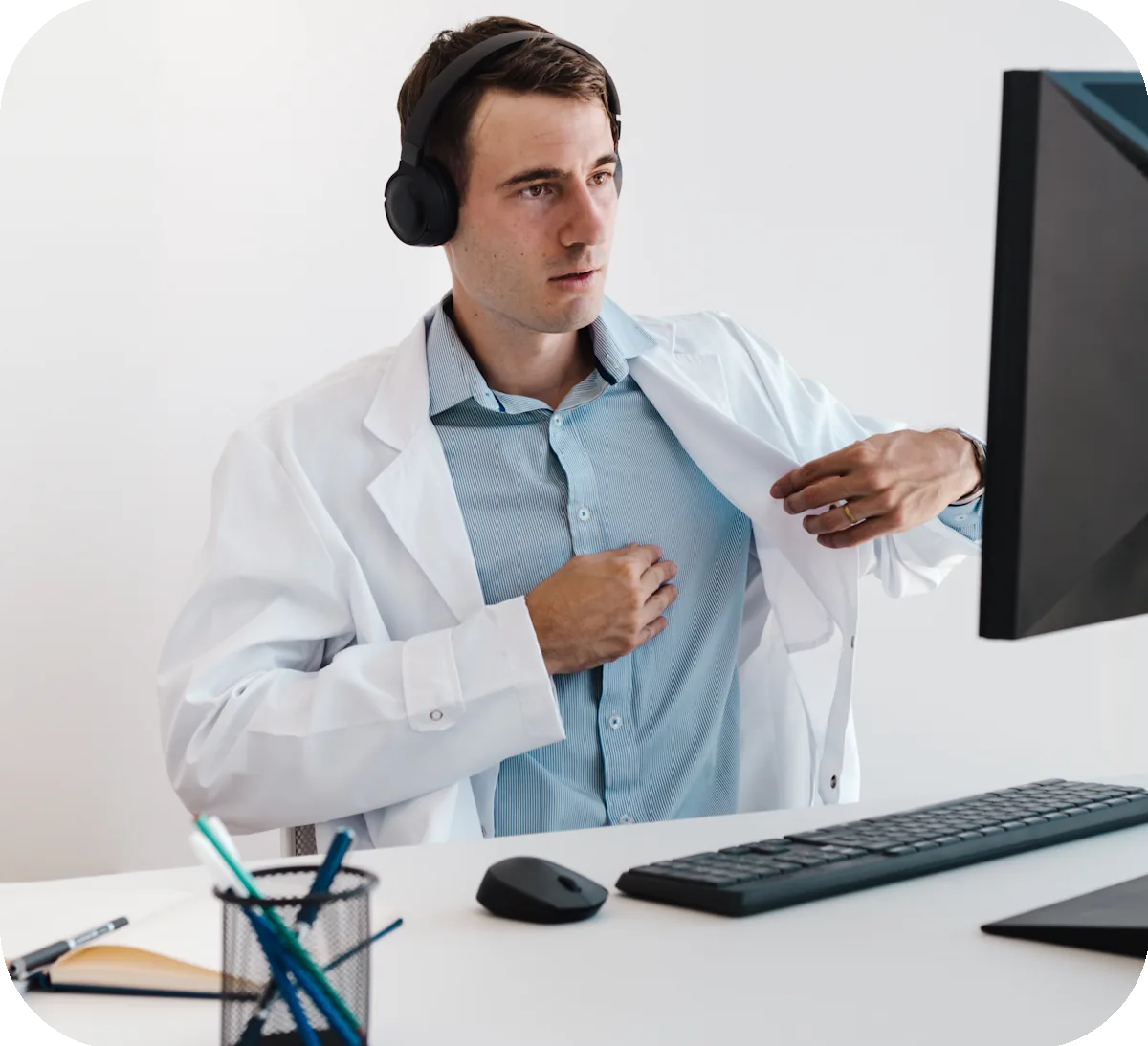 A doctor wearing headphones reviews a consultation on a monitor